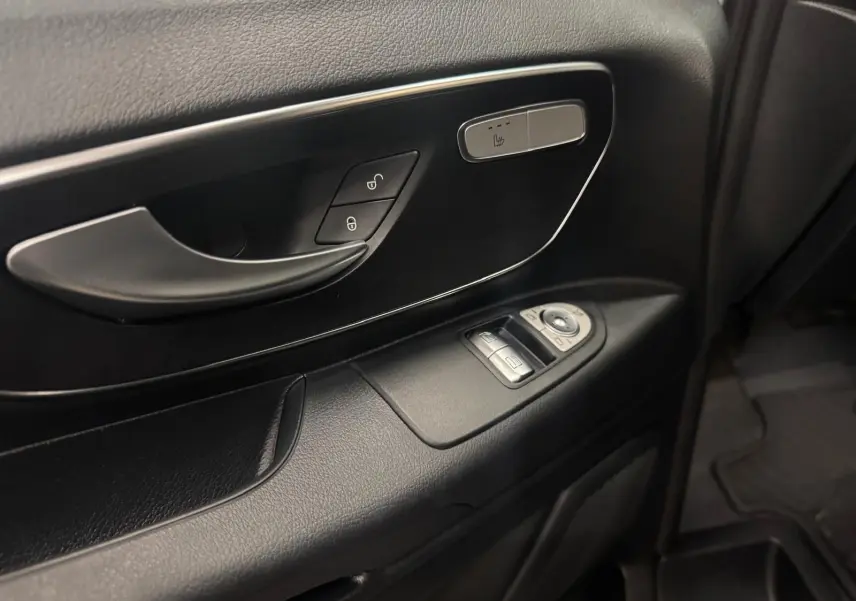 Gros plan sur la porte intérieure côté conducteur du Mercedes Vito Mixto 2025, avec commandes de vitres et bouton siège chauffant.