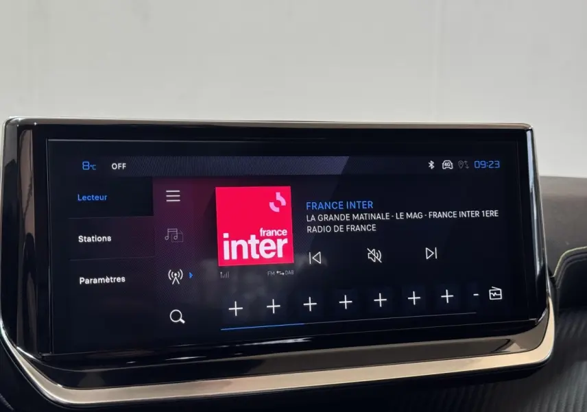 Écran tactile central de la Peugeot 208 Hybrid gris clair affichant la radio France Inter en intérieur.