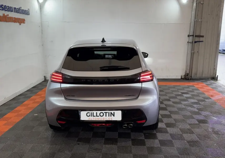 Vue arrière d'une Peugeot 208 Hybrid gris clair avec feux LED allumés dans un garage.
