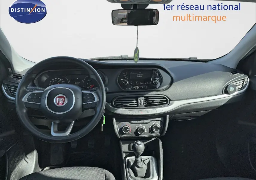 Vue intérieure avant du tableau de bord d'une Fiat Tipo 5 portes blanche de 2018 avec volant et levier de vitesses manuelle.