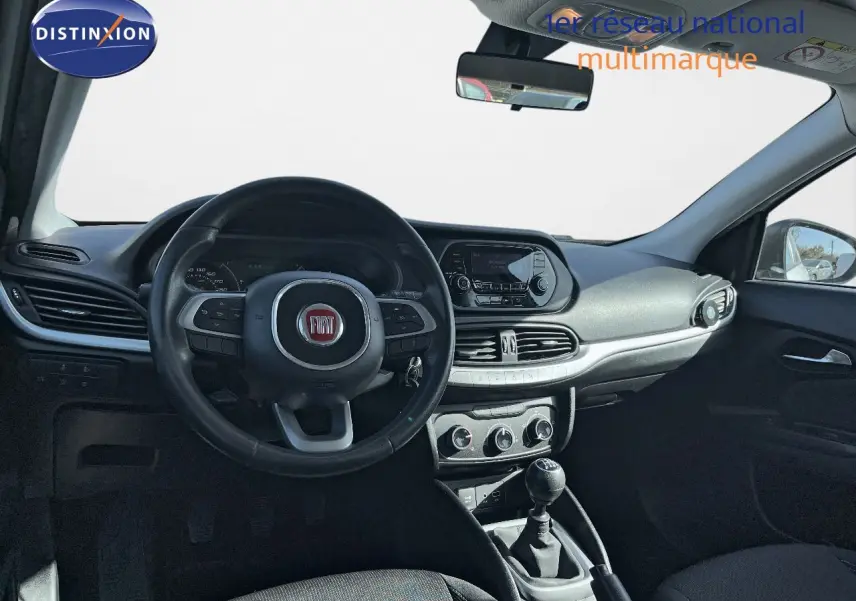 Intérieur de la Fiat Tipo 5 portes blanche, vue frontale sur le volant, tableau de bord et levier de vitesse manuel.
