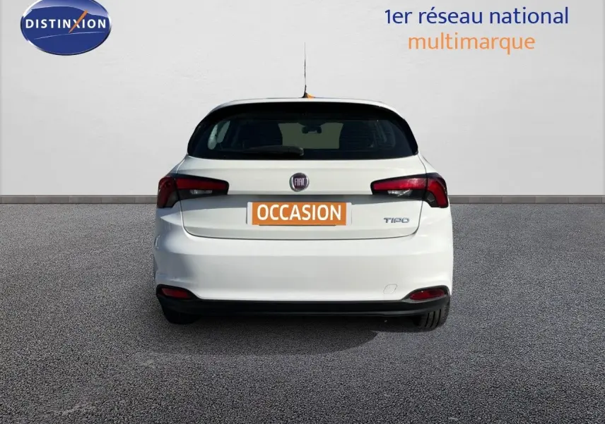 Vue arrière d'une Fiat Tipo 5 portes blanche de 2018 avec logo et feux arrière distinctifs, stationnée sur sol gris.