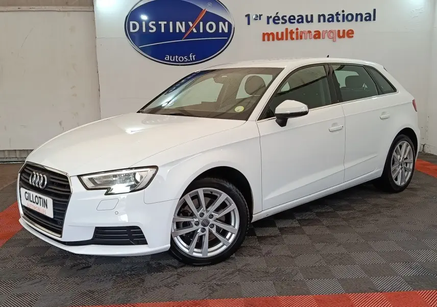 Audi A3 blanc vue 3/4 avant droit, avec jantes alliage et phares LED, en intérieur showroom.
