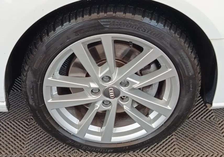 Gros plan sur la roue avant droite argentée d'une Audi A3 blanche, mettant en valeur la jante en alliage et le pneu Bridgestone.