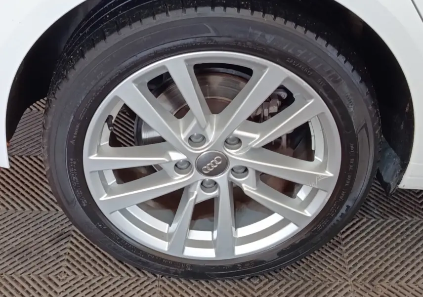 Gros plan sur la roue avant droite argentée d'une Audi A3 blanche, mettant en valeur la jante en alliage.