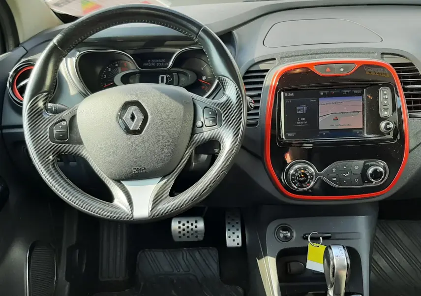 Vue intérieure frontale du tableau de bord du Renault Captur gris cassiopée, volant cuir noir, écran tactile avec cadre orange.
