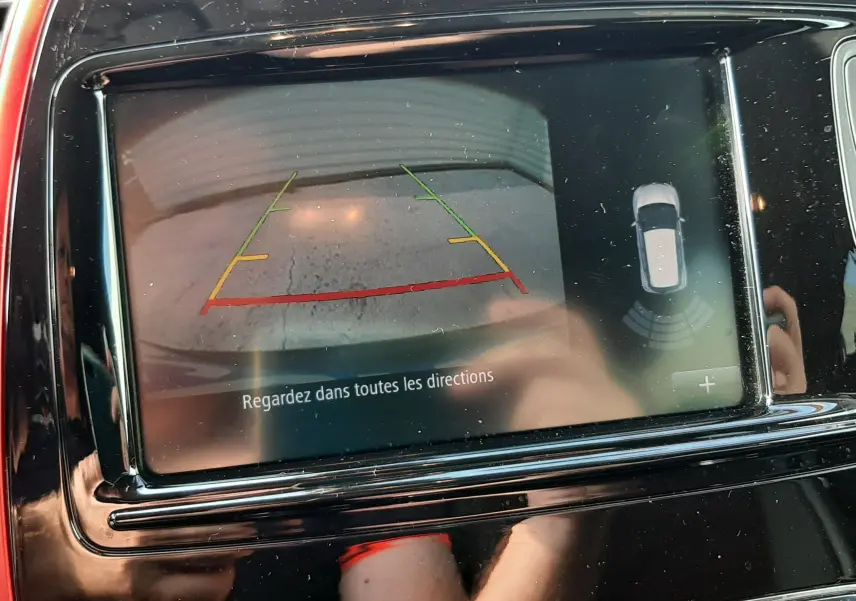 Écran central rouge et noir du Renault Captur montrant la caméra de recul avec guidage de trajectoire coloré.