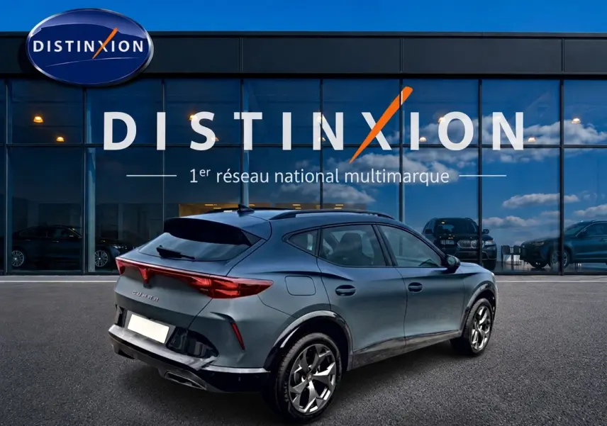 Vue 3/4 arrière droite d'un CUPRA Formentor bleu fjord avec jantes 18 pouces devant un showroom Distinxion.