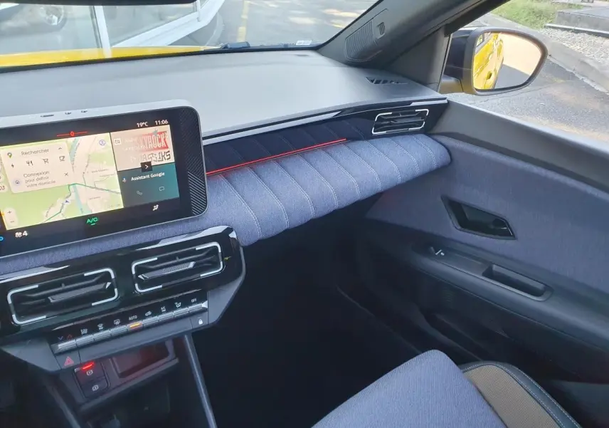 Vue intérieure côté passager de la Renault R5 E-Tech jaune, avec tableau de bord moderne et écran tactile connecté.