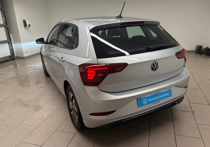 Volkswagen Polo 2024 argent métallisé vue 3/4 arrière droit en intérieur avec feux arrière allumés.