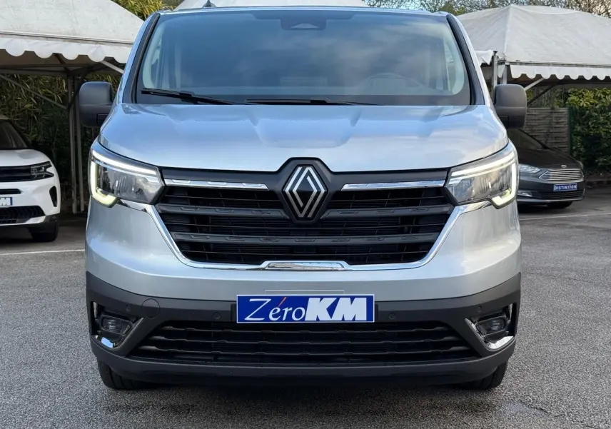 Vue rapprochée du volant noir et du tableau de bord du Renault Trafic cabine approfondie gris Highland, avec levier de vitesses manuel visible.