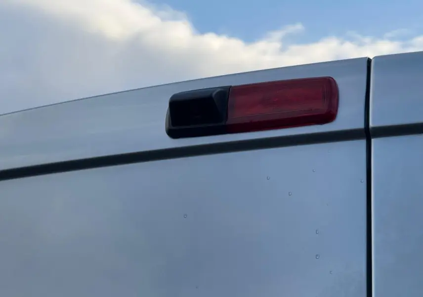 Vue 3/4 avant droit d'un Renault Trafic cabine approfondie gris Highland avec calandre noire et jantes argentées.