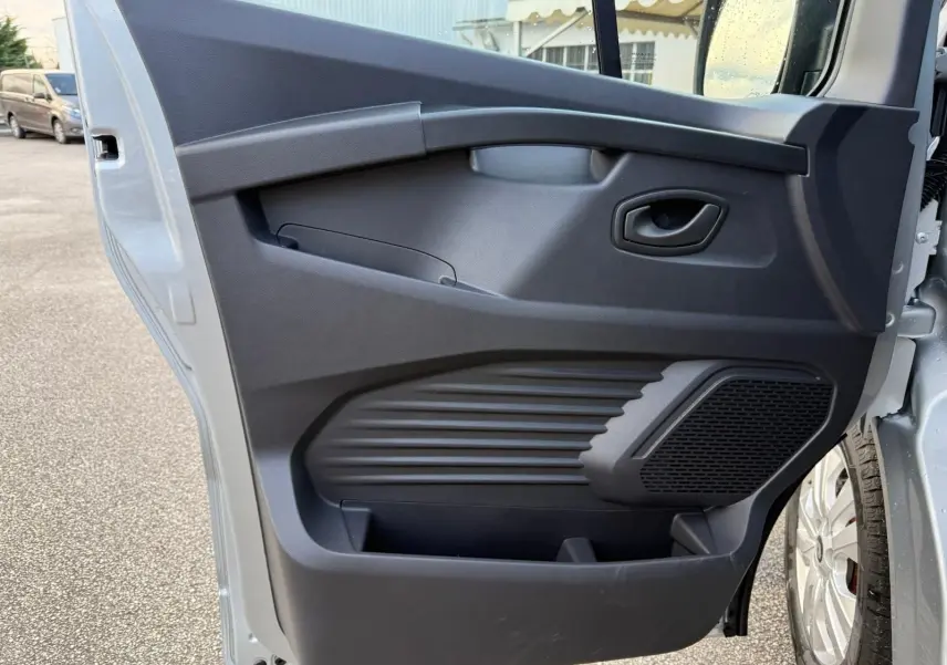 Écran tactile central du tableau de bord du Renault Trafic cabine approfondie 2025 avec commandes climatisation et radio visibles.