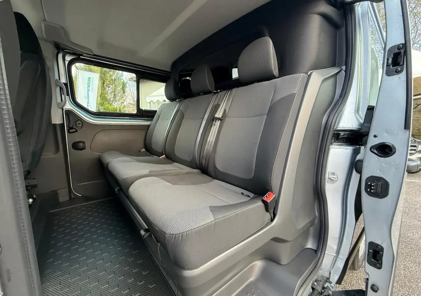 Renault Trafic cabine approfondie gris Highland vu en 3/4 avant droit, avec grandes fenêtres latérales et jantes acier.