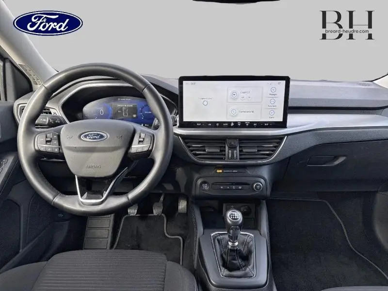 Vue intérieure avant de la Ford Focus SW 2023 gris lunaire, volant cuir multifonction et écran tactile central.