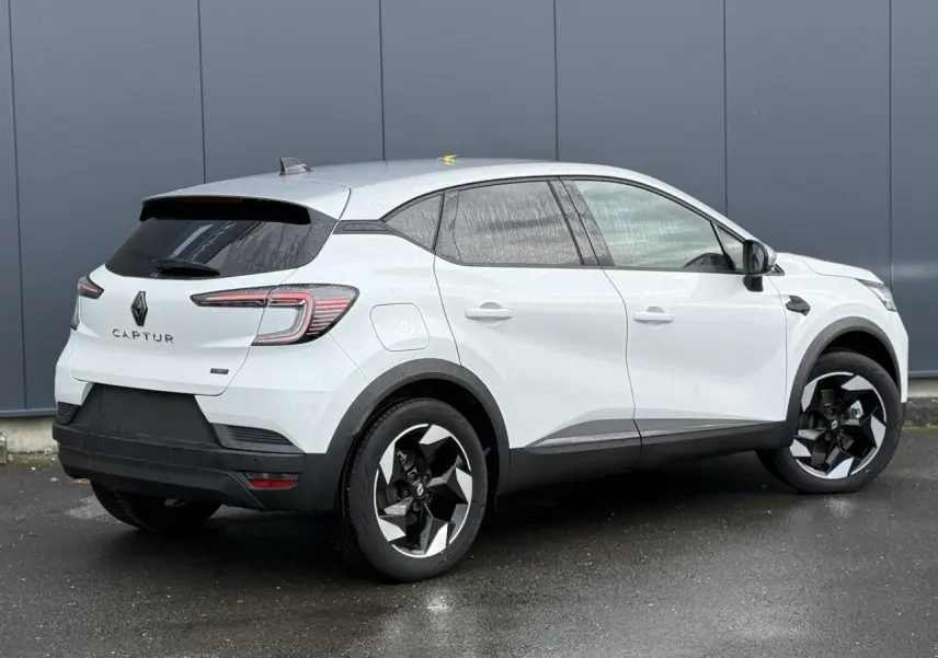 Renault Captur hybride 2025 blanc nacré vue 3/4 arrière côté droit avec toit gris et jantes noires.