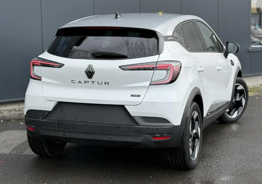 Vue 3/4 arrière droite d'un Renault Captur blanc nacré avec toit gris Highland et jantes noires 18 pouces.