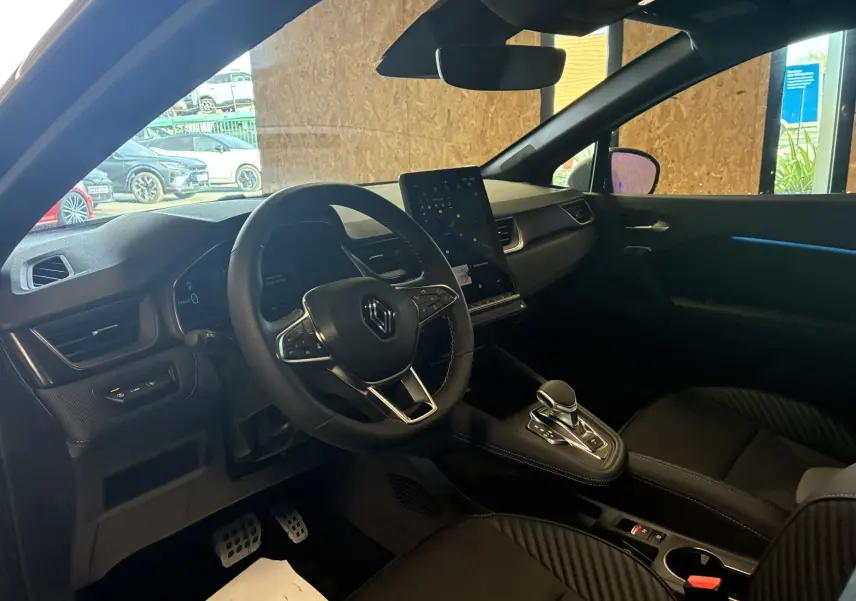 Intérieur noir du Renault Captur E-Tech 2025 vu côté conducteur, avec volant multifonction et écran tactile vertical.