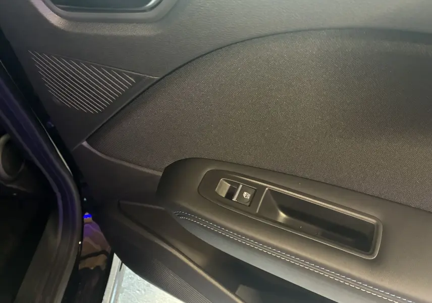 Gros plan sur la porte intérieure côté gauche du Renault Captur E-Tech noir étoile avec bouton de commande de vitre et surpiqûres bleues.