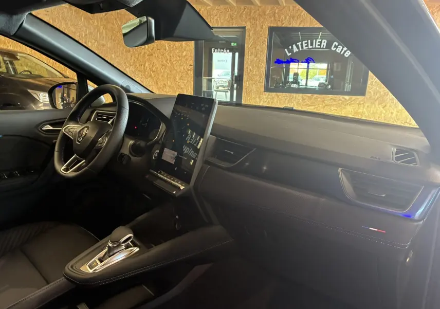 Intérieur du Renault Captur E-Tech 2025 vu côté passager, tableau de bord noir avec écran tactile vertical et finitions Alpine.