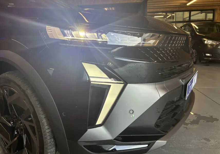 Gros plan sur l'avant droit du Renault Captur E-Tech noir étoile avec toit gris, mettant en valeur ses phares LED et la calandre distinctive.