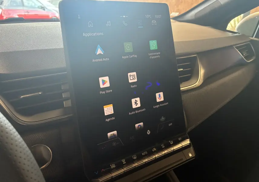 Vue intérieure du tableau de bord du Renault Captur E-Tech 2025, écran tactile vertical avec applications connectées visibles.