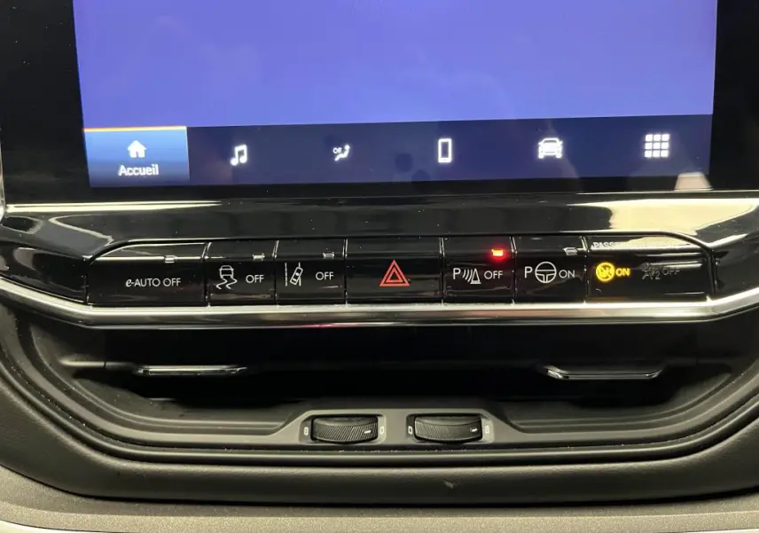 Tableau de bord du Jeep Compass 2024 avec commandes de sécurité et assistance, boutons noirs et écran tactile partiel.