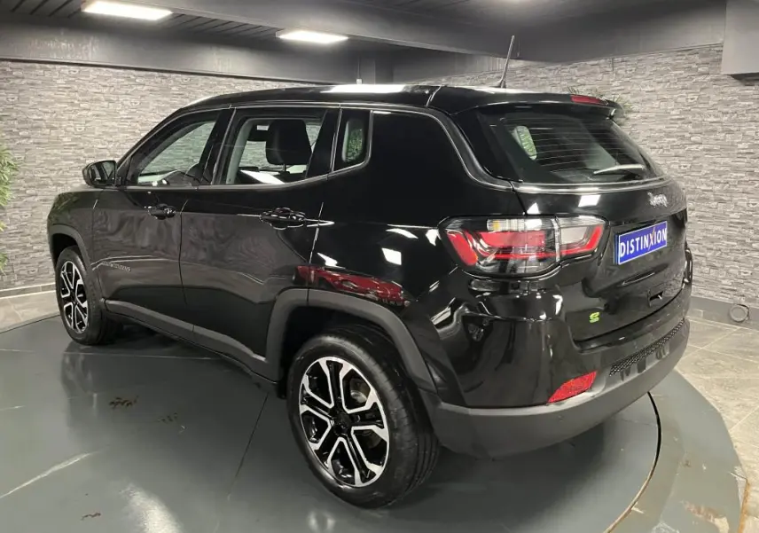 Jeep Compass noir en vue 3/4 arrière droit, avec jantes alliage noires et détails extérieurs brillants en intérieur showroom.