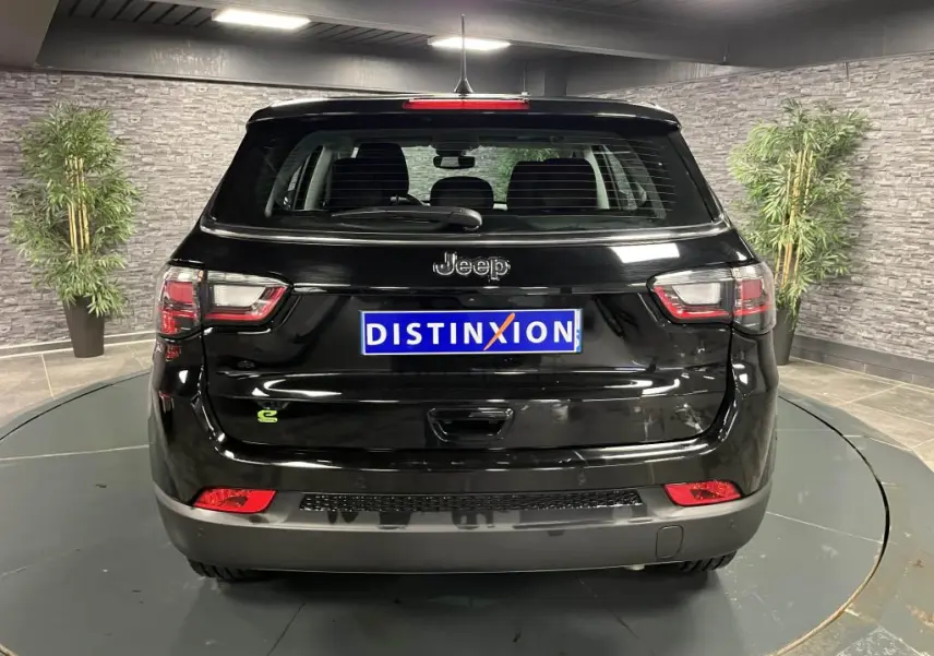 Vue arrière d'un Jeep Compass noir 2024 avec logo e-Hybrid et feux arrière LED dans un showroom.