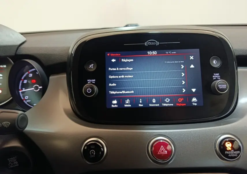 Vue rapprochée du tableau de bord gris avec écran tactile central affichant le menu réglages sur FIAT 500X noir.