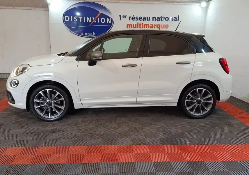 Profil droit d'une FIAT 500X blanche avec toit noir, jantes alliage et logo Sport sur l'aile avant.