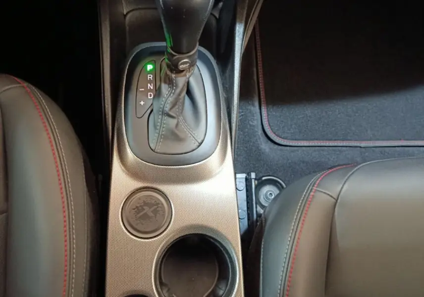 Vue plongeante sur la console centrale noire de la FIAT 500X 2021 avec levier de boîte auto et surpiqûres rouges.