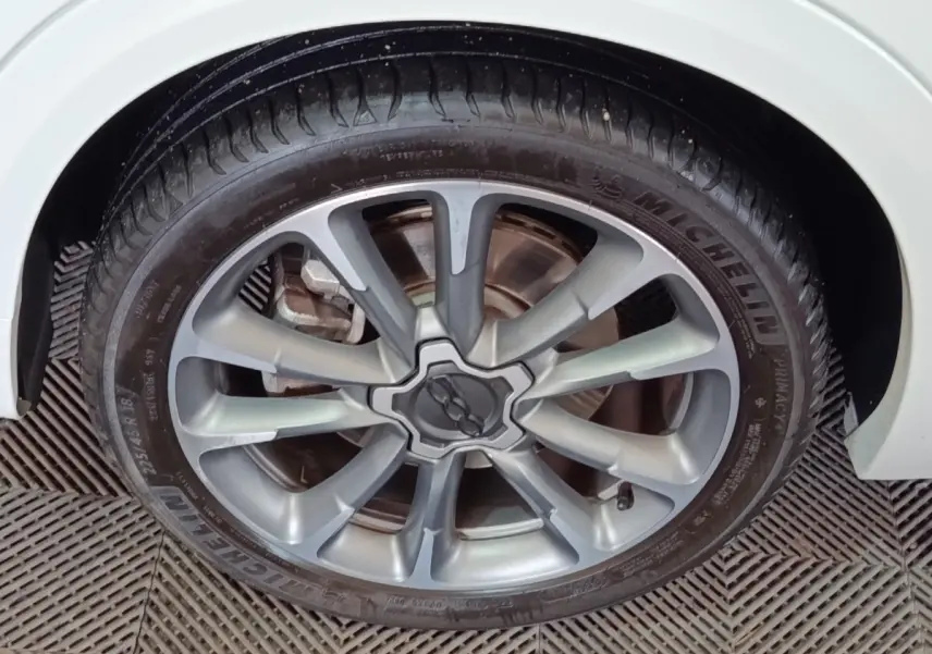 Gros plan sur la jante alliage argentée avec logo FIAT au centre d’une roue de FIAT 500X blanche.