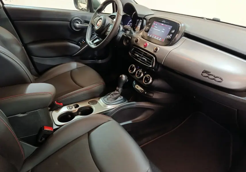 Vue intérieure côté conducteur de la FIAT 500X noire, avec tableau de bord moderne et écran tactile central.