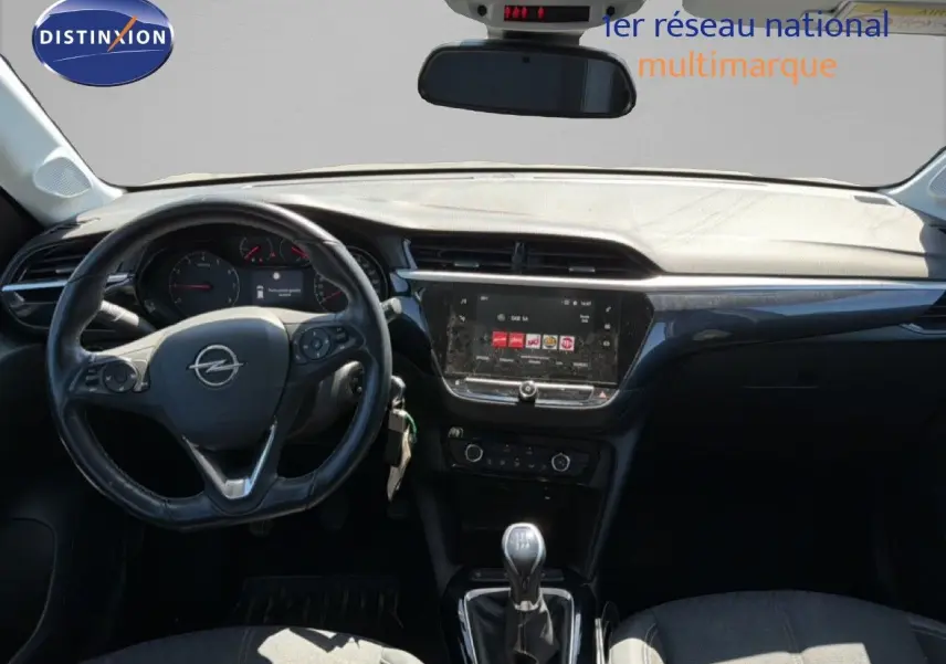 Vue intérieure frontale de l’Opel Corsa gris quartz, montrant le volant, tableau de bord et levier de vitesses manuel.