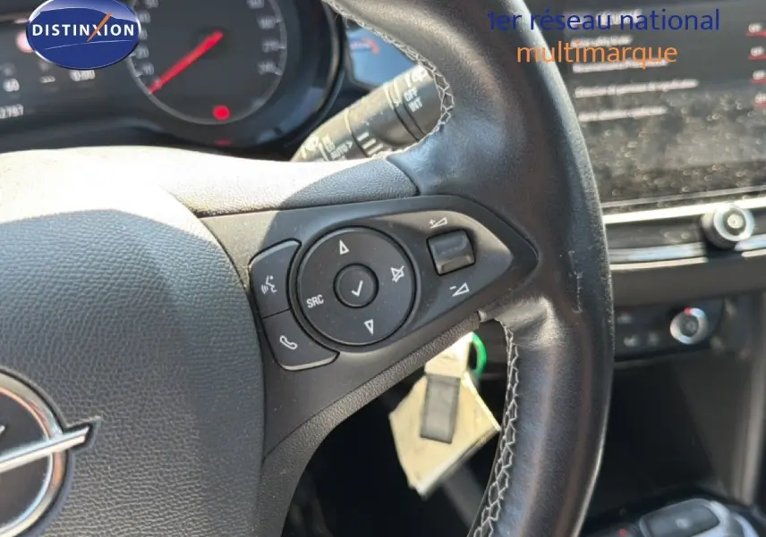 Vue rapprochée du volant en cuir noir de l’Opel Corsa gris quartz métal, avec commandes audio intégrées.