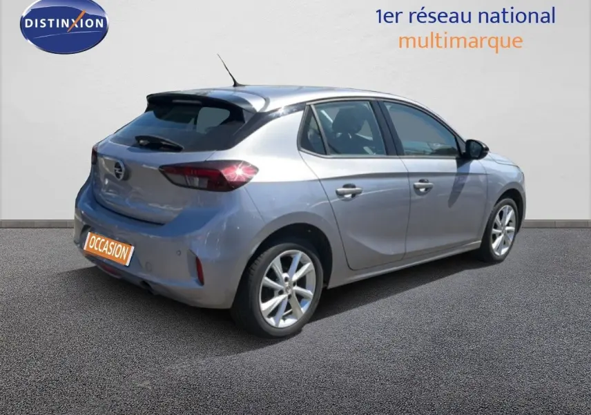 Opel Corsa gris quartz métal vue 3/4 arrière côté droit, avec feux arrière allumés et jantes alliage.