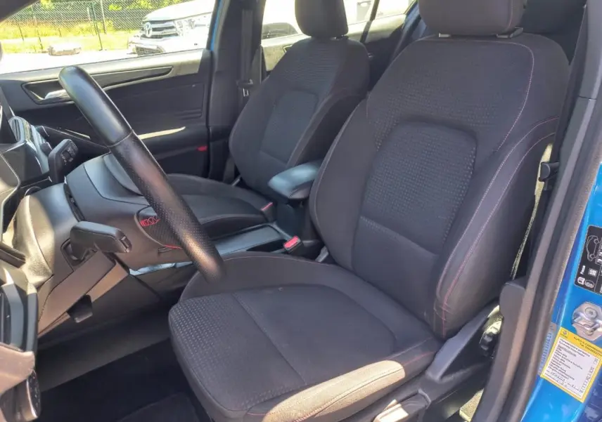 Intérieur de la Ford Focus 2019 bleu, vue côté conducteur montrant sièges noirs avec surpiqûres rouges et volant cuir.
