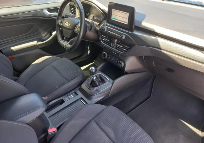Vue intérieure côté conducteur de la Ford Focus 2019, montrant le tableau de bord, volant et levier de vitesse manuel.