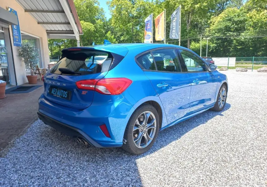 Vue 3/4 arrière droite d'une Ford Focus ST-Line bleu vif de 2019, avec jantes alliage et double sortie d'échappement.