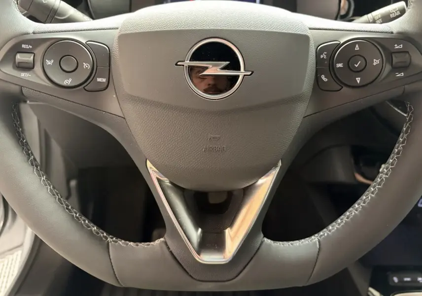 Gros plan sur le volant cuir synthétique noir de l'Opel Corsa 2025 avec commandes multifonctions intégrées.