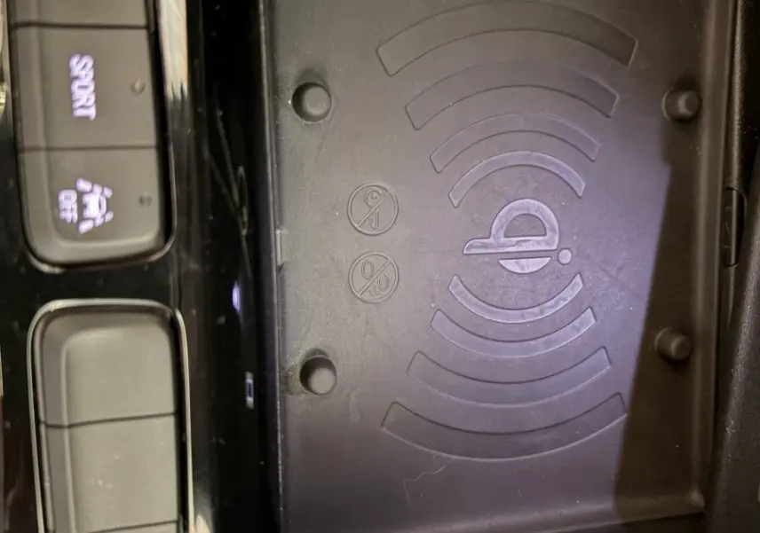 Gros plan sur la zone de recharge sans fil et les boutons de commande noirs brillants dans une Opel Corsa gris clair.