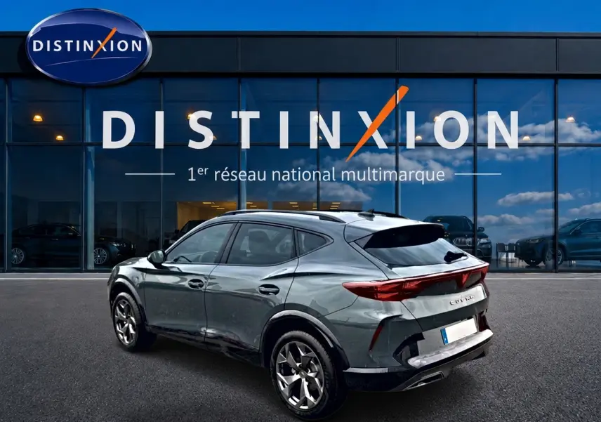 Vue 3/4 arrière droite d'un CUPRA Formentor gris métallisé avec feux arrière LED et jantes 18 pouces devant un showroom.