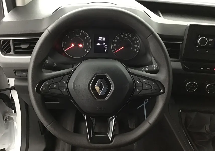 Vue rapprochée du volant noir du Renault Kangoo blanc 2022, avec commandes intégrées et tableau de bord visible.