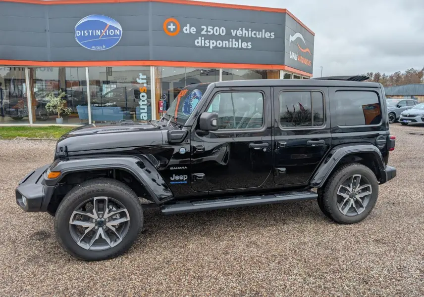 Jeep Wrangler Sahara noir en profil droit, avec jantes alliage 20 pouces et marche-pied visible.