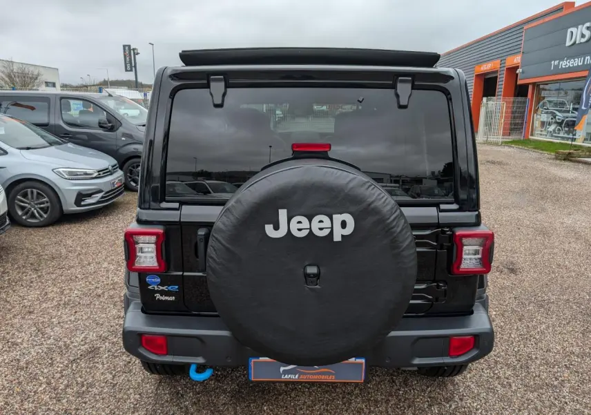 Vue arrière d'un Jeep Wrangler noir avec roue de secours couverte et feux arrière LED carrés.