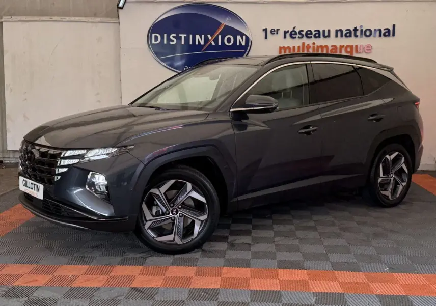 Vue 3/4 avant gauche d'un Hyundai Tucson gris foncé avec jantes au design moderne, stationné en intérieur showroom.