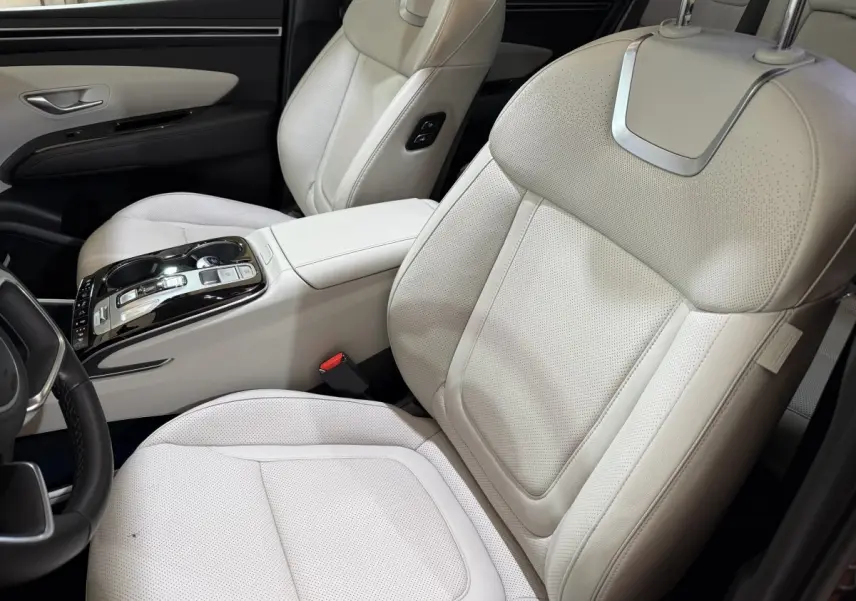 Vue intérieure côté conducteur du Hyundai Tucson 1.6 Hybrid 230 Executive avec sièges en cuir beige clair et console centrale moderne.