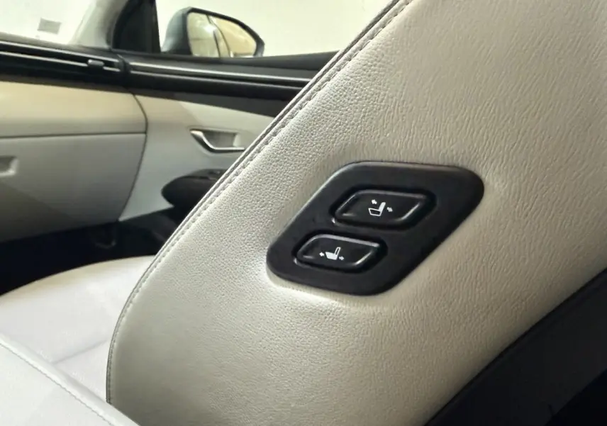 Détail des commandes de réglage des sièges arrière en cuir clair dans un Hyundai Tucson gris foncé.