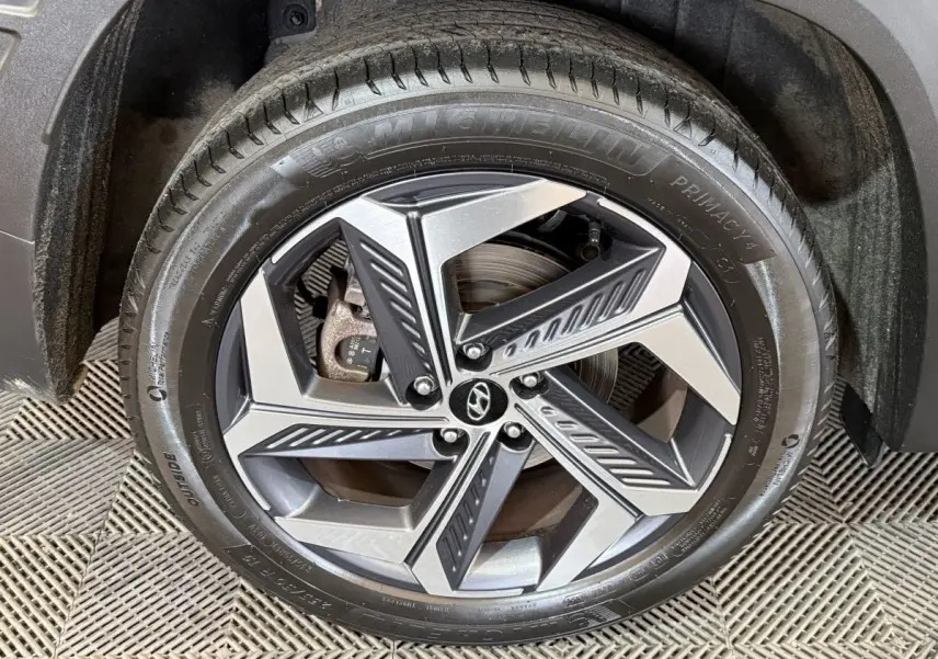 Gros plan sur la roue avant droite du Hyundai Tucson gris foncé, mettant en valeur la jante alliage au design moderne.